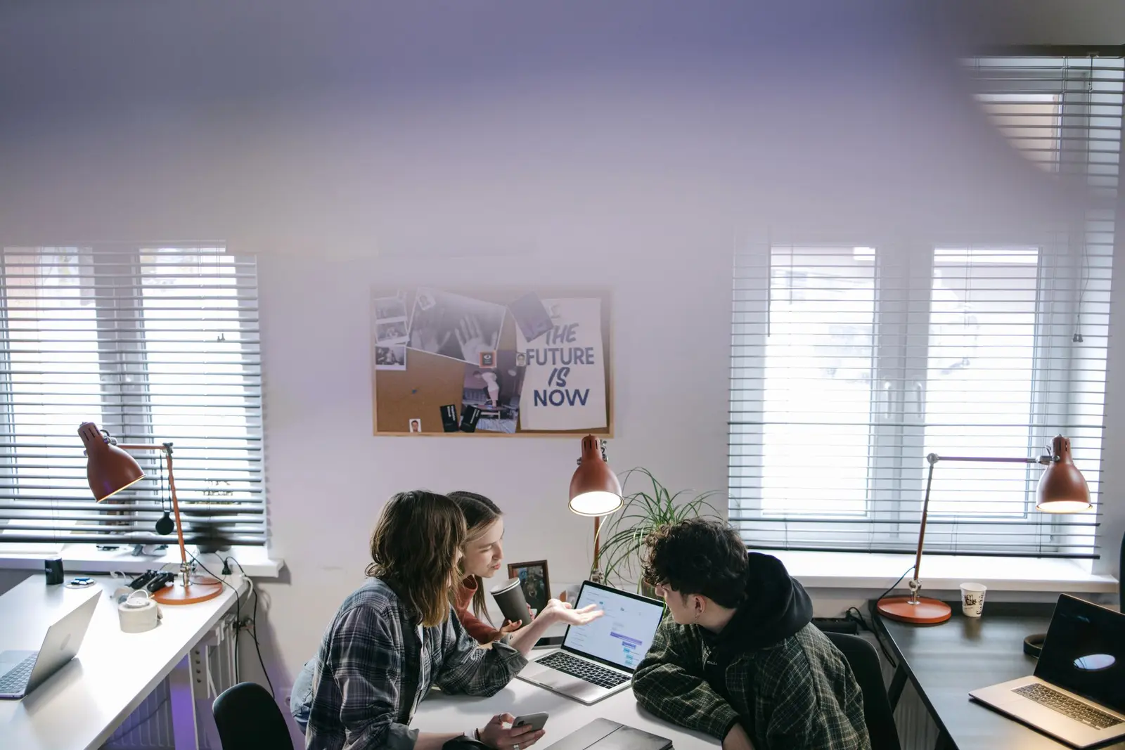 Jeunes professionnels qui travaillent ensemble autour d'ordinateurs