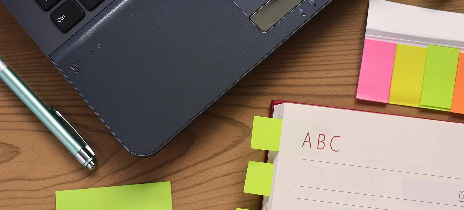 Bureau avec stylo, cahier, notes autocollantes et ordinateur portable